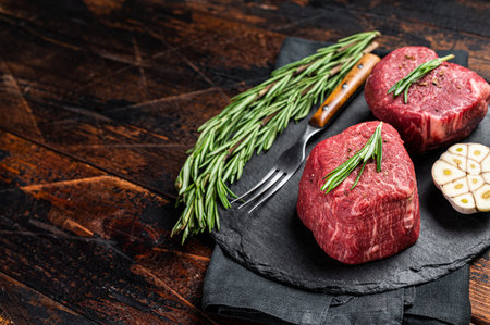 Raw Fillet Mignon Beef steak with herbs and garlic, marble meat. Wooden background. Top view. Space for text.の写真素材