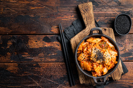 Kimchi salted and fermented Chinese cabbage in a skillet. Wooden background. Top view. Copy space.の写真素材