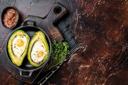 Baked Avocado with Egg, Salt, thyme and Pepper. Dark background. Top view. Copy space.の写真素材