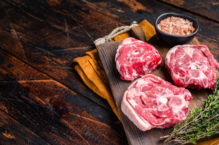 Fresh Raw lamb neck meat with bone on a wooden board with herbs. Wooden background. Top view. Copy space.の写真素材
