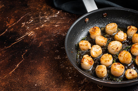Fried scallops with butter lemon sauce in a skillet. Dark background. Top view. Copy space.の写真素材
