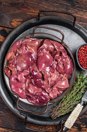 Fresh Raw chicken liver, poultry giblets in steel tray with herbs. Wooden background. Top view.の写真素材