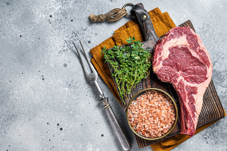 Raw uncooked black angus beef cowboy or rib eye steak. Gray background. Top view. Copy space.の写真素材