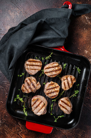 Fried pork medallions steaks from tenderloin meat on a grill skillet. Dark background. Top view.の写真素材