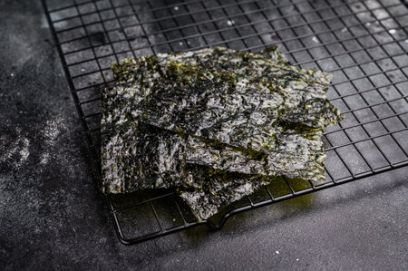 Dried Nori seaweed sheets on a rack. black background. top view.