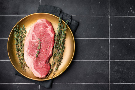 Raw Striploin steak, New York strip beef steak in a plate with herbs. black background. top view.の写真素材