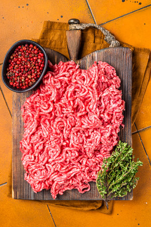 Fresh Raw Mince, Ground beef and pork meat on a butcher board. Orange background. Top viewの写真素材