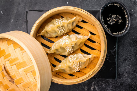 Steamed Japanese Gyoza Dumplings with pork meat and vegetables in bamboo steamer. black background. top view.の写真素材