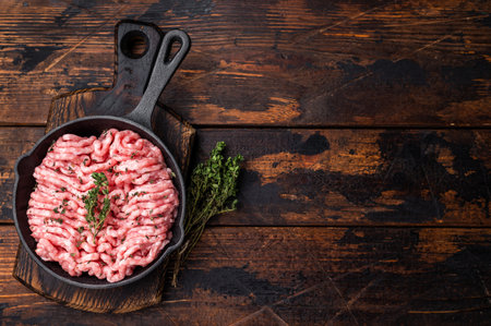 Ready for cooking raw ground pork and beef meat, fresh mince meat in skillet. wooden background. top...