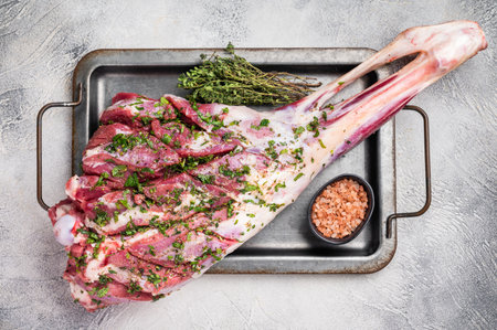 Marinated with herbs and olive oil raw goat leg. white background. top view.の写真素材
