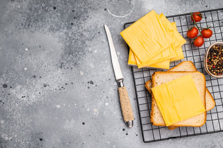 Square Slices of processed Cheddar cheese in individual plastic packaging. gray background. top view.の写真素材