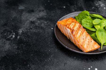 Roast salmon fillet steak with spinach. black background. top view.の写真素材