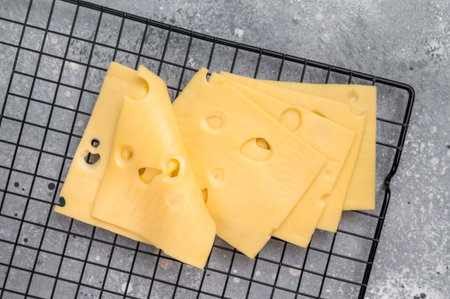Maasdam cheese slices on kitchen table. grey background. top view.