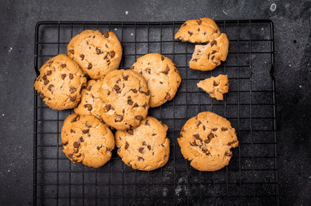 Baked Chocolate chip cookies on steel rack. black background. top view.