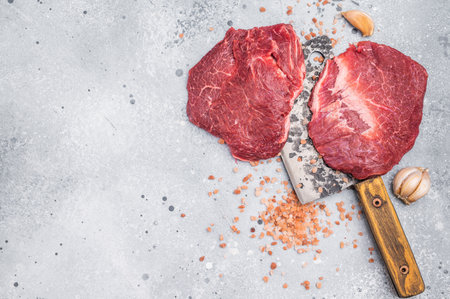 Raw beef cheeks on butcher meat cleaver. gray background. top view.の写真素材