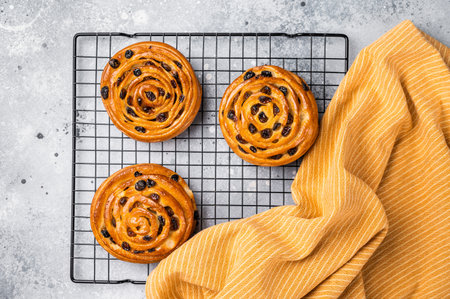 Baked Danish pastry, raisin bun on steel rack. grey background. top viewの写真素材
