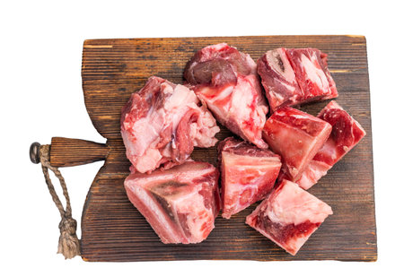 Raw diced Beef meat with bones for stew or goulash on wooden board isolated on white background. top view.の写真素材