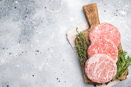 Frozen raw Hamburger beef Patty, uncooked mincemeat. gray background. top view.の写真素材