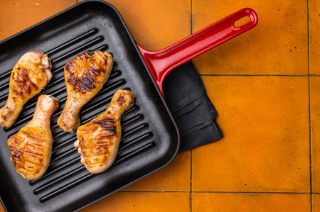 Succulent grilled drumsticks, marinated to perfection and served hot off the grill for a delightful dining experience. orange background. top view.の写真素材