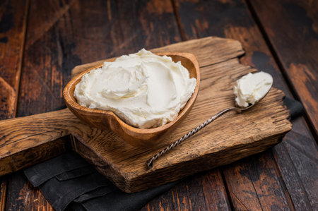 Traditional Mascarpone cheese in wooden bowl. wooden background. top view.の写真素材