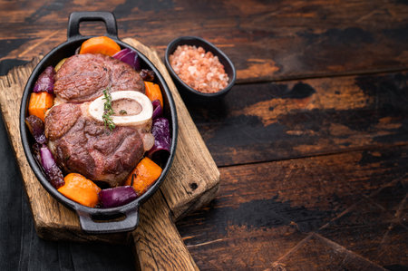 Hearty ossobuco slow cooked to perfection, showcasing succulent osso buco shank meat and aromatic herbs in a comforting stew. wooden background. top view.の写真素材