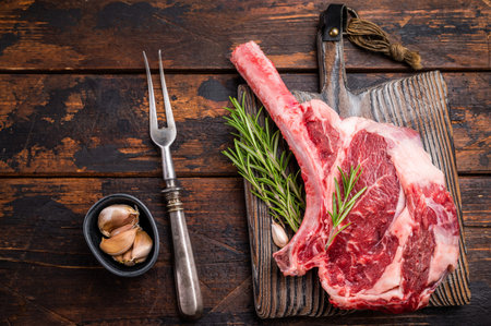 Raw Tomahawk beef steak, fresh black angus ribeye with bone on wooden board. wooden background. top view.の写真素材