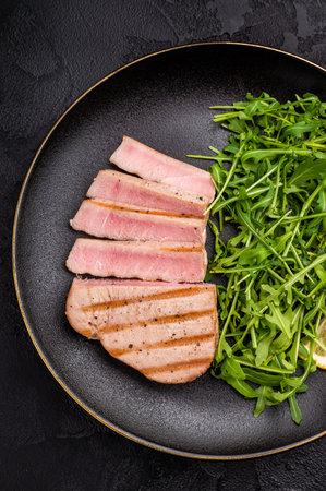 Succulent grilled tuna steak, showcasing vibrant color and rich taste, perfect for summer barbecues and elegant dinners. black background. top view.の写真素材
