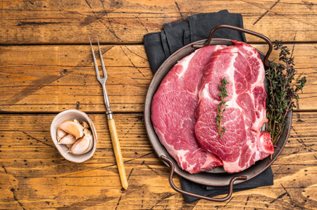 Uncooked pork tender steak, raw sliced neck meat with thyme. wooden background. top view.の写真素材
