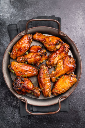 Savory grilled chicken wings smothered in tangy barbecue sauce, the ultimate treat for meat lovers and party enthusiasts. black background. top view.の写真素材