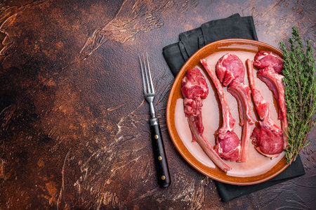 Uncooked lamb chops, fresh mutton meat steaks on a plate. brown background. top view.の写真素材