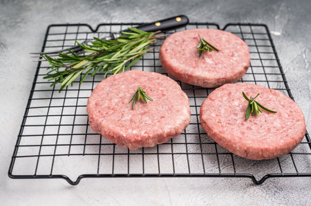 Close up of a juicy raw meat patty cutlet, ideal for crafting mouthwatering sandwiches and savory dishes. white background. top view.の写真素材