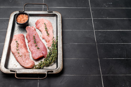 Ready for cooking Raw pork fillet steaks, loin chops with herbs and in a kitchen tray. black...