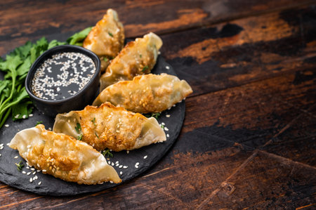 Fried Gyoza on plate with sauce, Japanese Dumplings with shrimps and vegetables. wooden background. top view.の写真素材