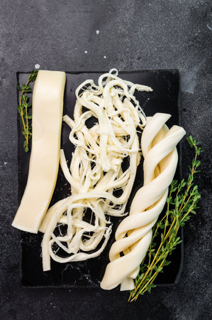 Assortiment of Traditional Caucasian Chechil white cheese on black board, top view