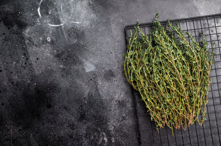 Fresh Herb thyme, sprigs bunch on a rack. black background. top view.