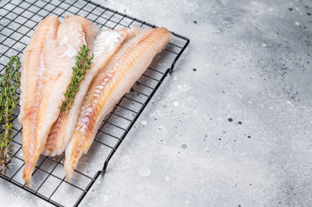 Raw pollock white fish fillet with thyme. gray background. top view.