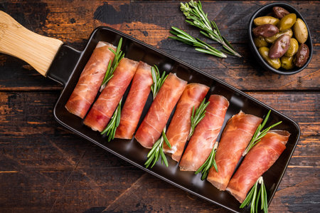 Appetizing plate of thinly sliced cured Italian ham (Prosciutto Crudo) garnished with rosemary sprigsの写真素材