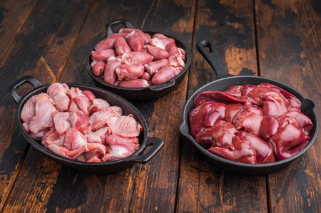 Raw chicken hearts in a frying pan on a dark wooden background.の写真素材