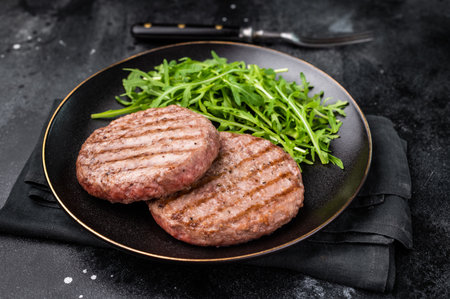 Grilled beef and pork meat patty paired with fresh veggies, an essential component for gourmet burgers. black background. top view.の写真素材