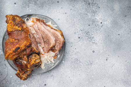 Crispy roasted pork knuckle with sliced tender shank meat served on sauerkraut over gray stone background with mustard and fork stylingの写真素材