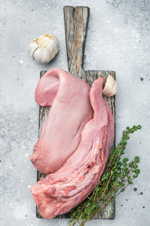 Whole uncooked lamb tongue displayed with herbs spices and vintage fork on light stone background.の写真素材