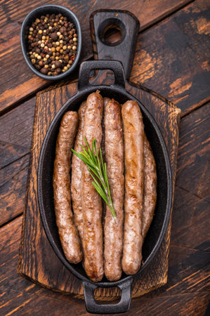 Delicious grilled sausage served with fresh herbs, a mouthwatering addition to any picnic or backyard party. wooden background. top view.の写真素材