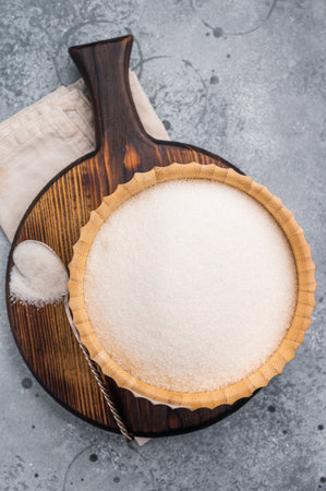 Versatile white sugar in a rustic bowl, ready to enhance desserts and beverages with its delightful sweetness. gray background. top view.の写真素材