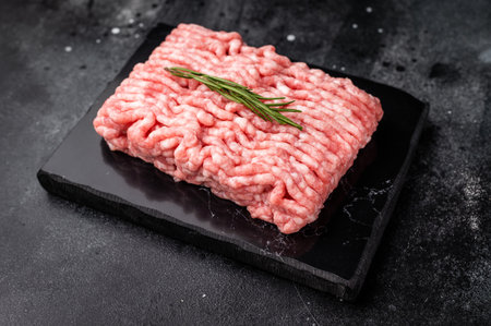 Raw Minced beef meat with rosemary on black slate board.の写真素材