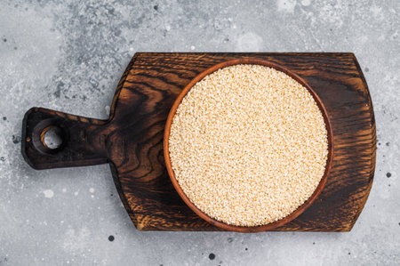 White sesame seeds in a wooden bowl. grey background. top view.の写真素材