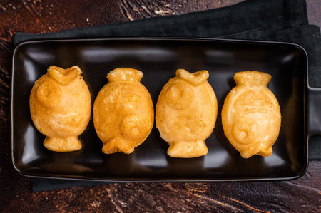 Japanese Taiyaki Fish Shaped Waffle with Sweet Paste. brown background. top view.の写真素材