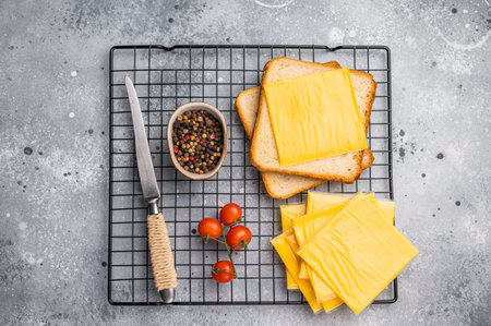 Square Slices of processed Cheddar cheese in individual plastic packaging. grey background. top view.の写真素材