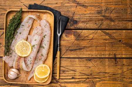 Raw Pollock and Hake fish fillets on a wooden board with herbs ready for cooking. wooden background....