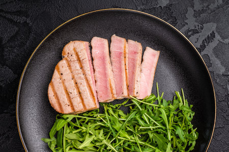 Succulent grilled tuna steak, showcasing vibrant color and rich taste, perfect for summer barbecues and elegant dinners. black background. top view.の写真素材