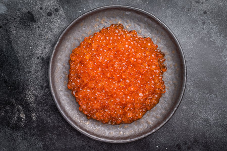 Luxurious red caviar, glistening pearls of flavor, perfect for elevating any gourmet dish or appetizer. black background. top view.の写真素材